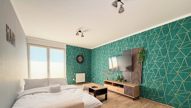 Una camera da letto moderna con un letto, una scrivania, una TV e una finestra.