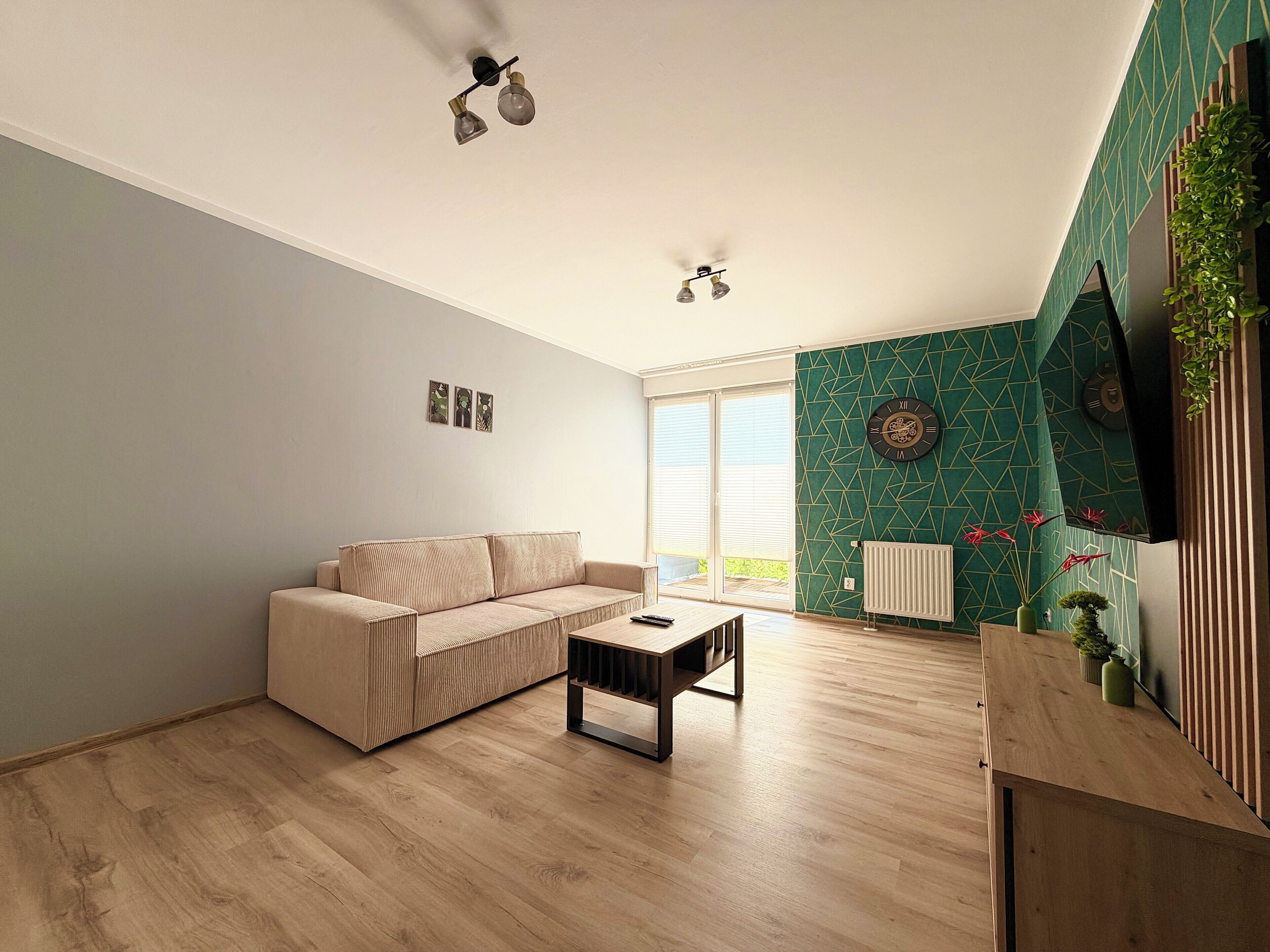 Una sala de estar moderna con un sofá color beige, una mesa de centro de madera y un ventilador de techo.