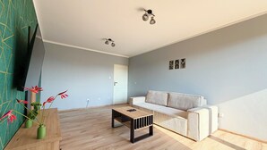 Un soggiorno spazioso con un tavolino in legno, un divano bianco e una parete verde decorativa.