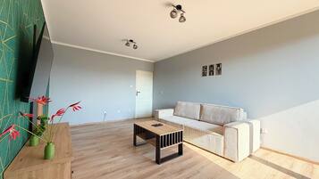 Un salón amplio con una mesa de centro de madera, un sofá blanco y una pared verde decorativa.