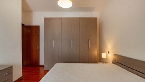 Une chambre à coucher avec un grand lit, une armoire en bois et une lampe de chevet.