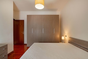 Une chambre à coucher avec un grand lit, une armoire en bois et une lampe de chevet.