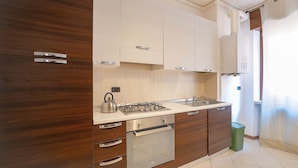 Une cuisine moderne avec des meubles en bois, une cuisinière en acier inoxydable et une poubelle verte.