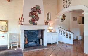 Ein geräumiges Wohnzimmer mit Kamin, einer Treppe und einer Wanduhr.