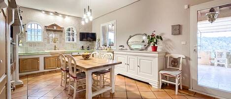 A spacious kitchen with a wooden dining table, white cabinetry, and a large window offering a view.