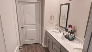 A bathroom with two sinks, a mirror, and a door. - NEW Charming 4-bedroom house with AC in vibrant Harlem (Harlem)