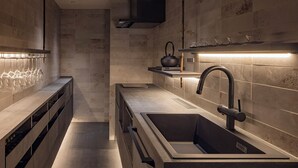 Een moderne keuken met een ingebouwd spoelgedeelte, een waterkoker en een plank met glazen.