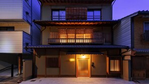 Un bâtiment à deux étages de style architectural japonais traditionnel, doté d’un balcon en bois et d’une entrée couverte.