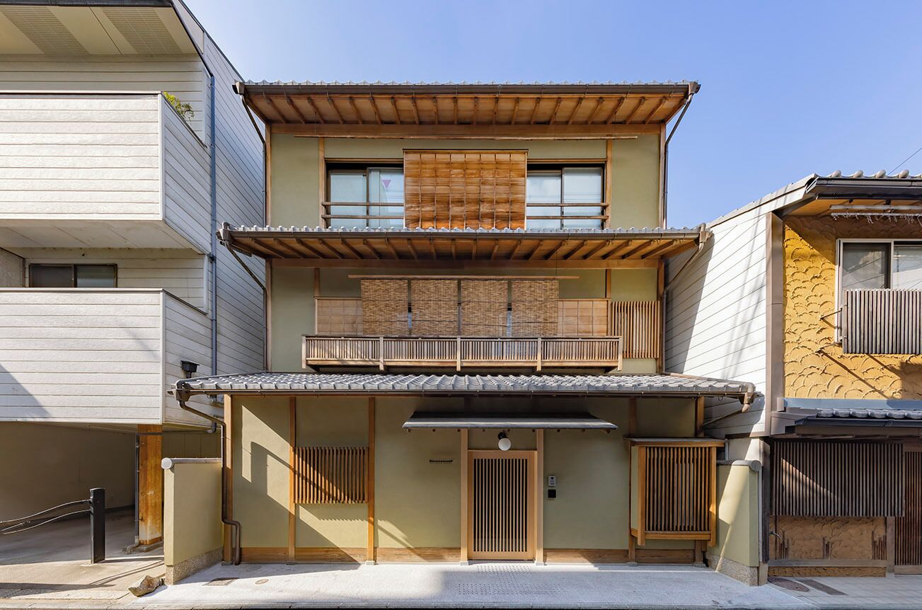 A traditional Japanese house with a two-story structure, a wooden balcony, and a tiled roof.