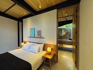 Un dormitorio con cama, mesitas de noche, lámpara, espejo y obras de arte en la pared.