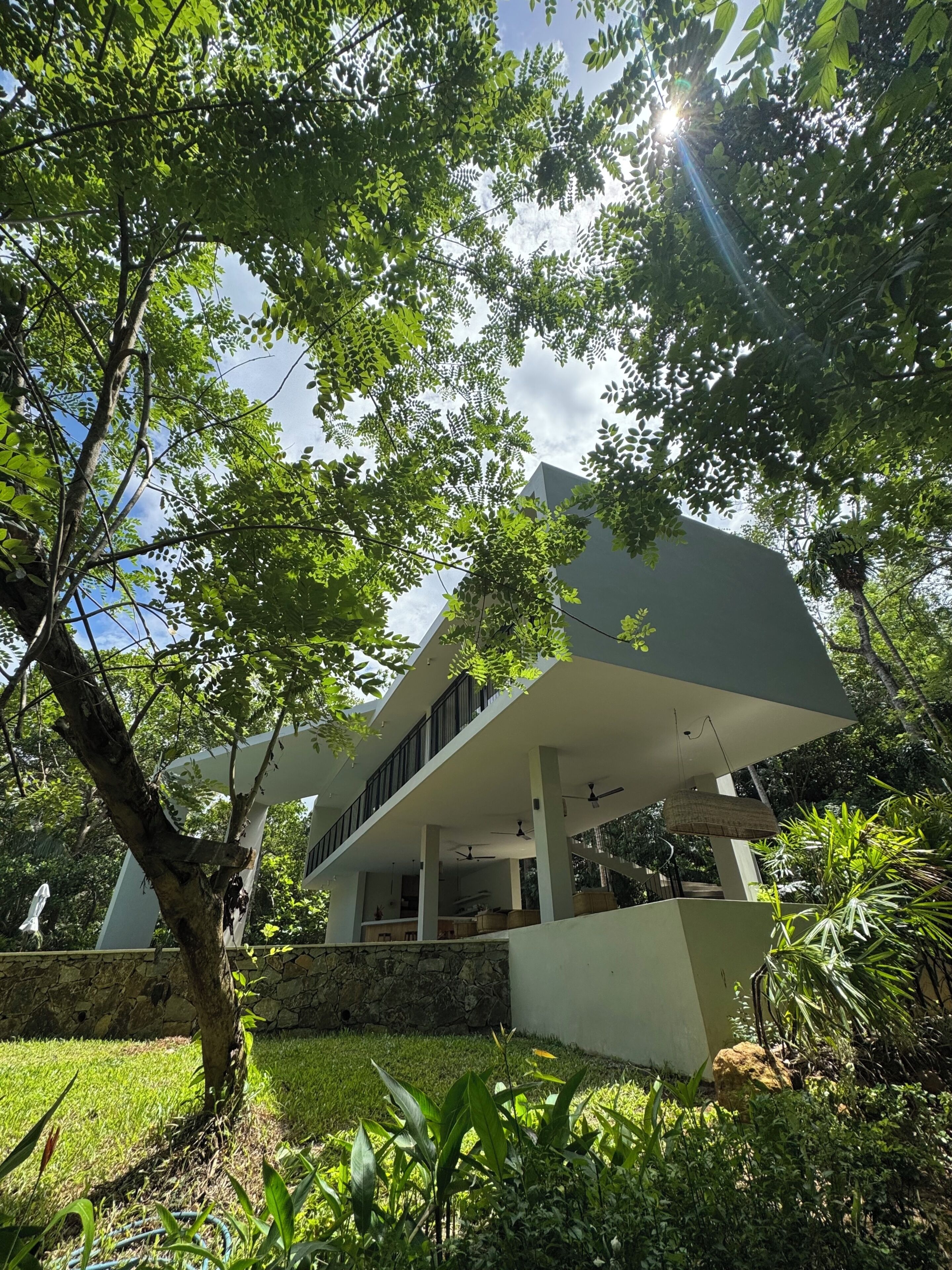 Una casa moderna con techo plano, ventanas amplias y un espacio exterior cubierto.