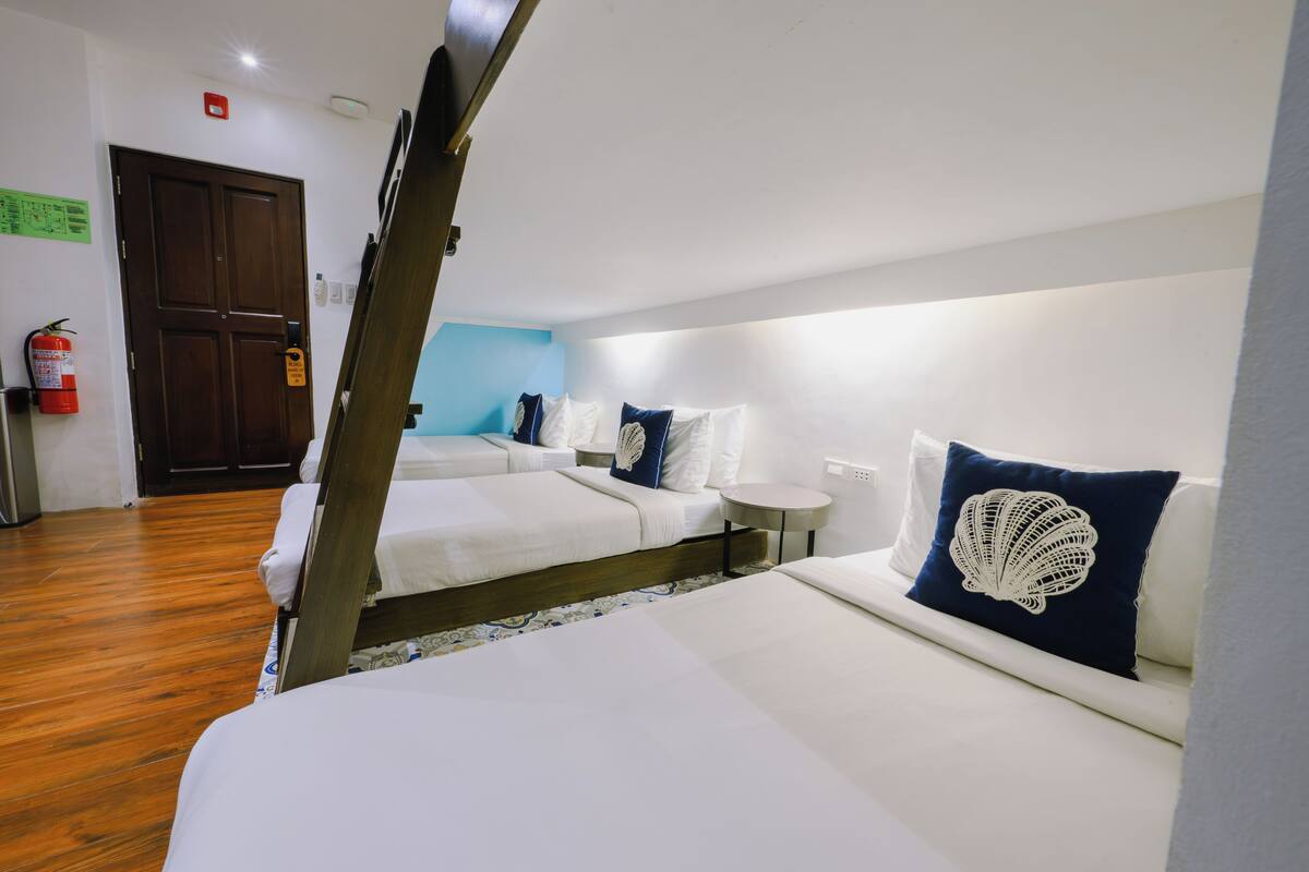 A hotel room with two beds, a wooden floor, a small round table, and a blue wall.