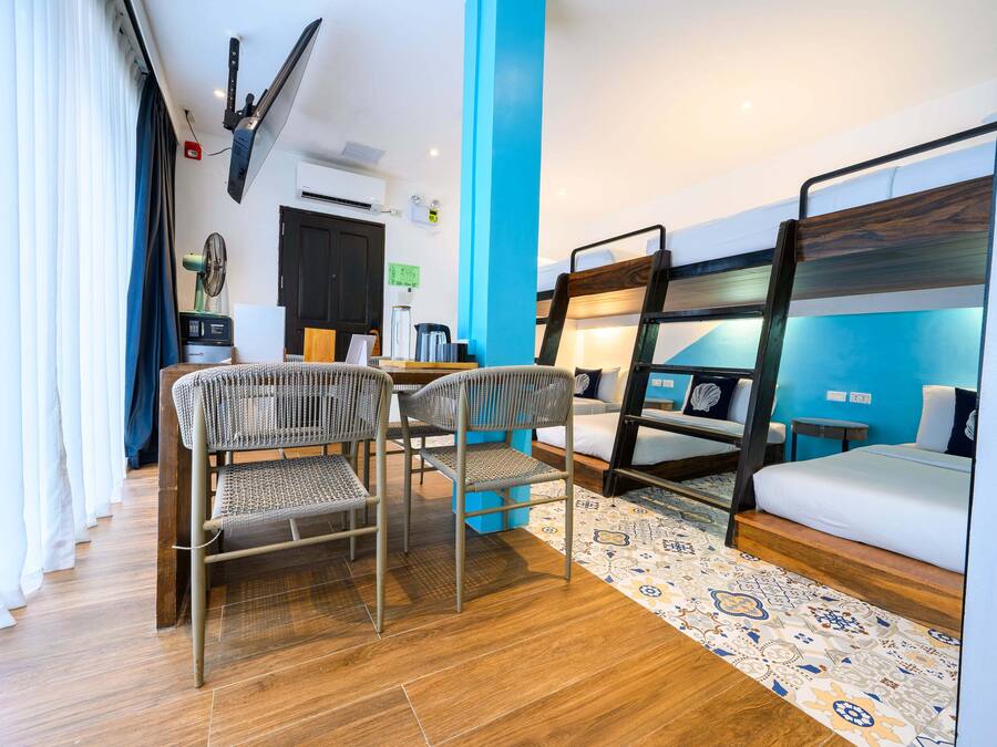 A room with bunk beds, a desk, chairs, and a patterned rug.
