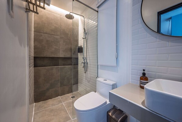 A modern bathroom with a glass-enclosed shower, a white toilet, and a sink with a mirror. - J Boutique El Nido Managed by H Hospital (El Nido)