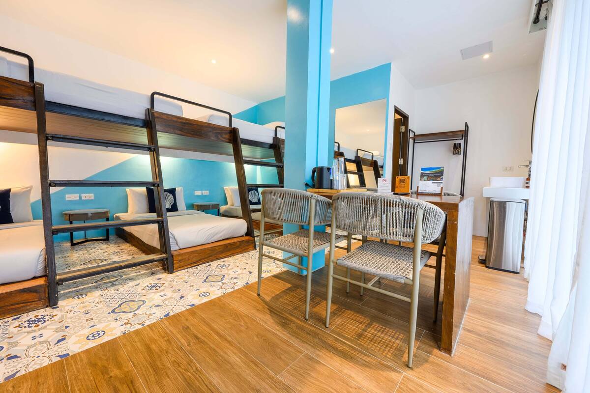 A bunk bed room with a desk, chair, and a small table.