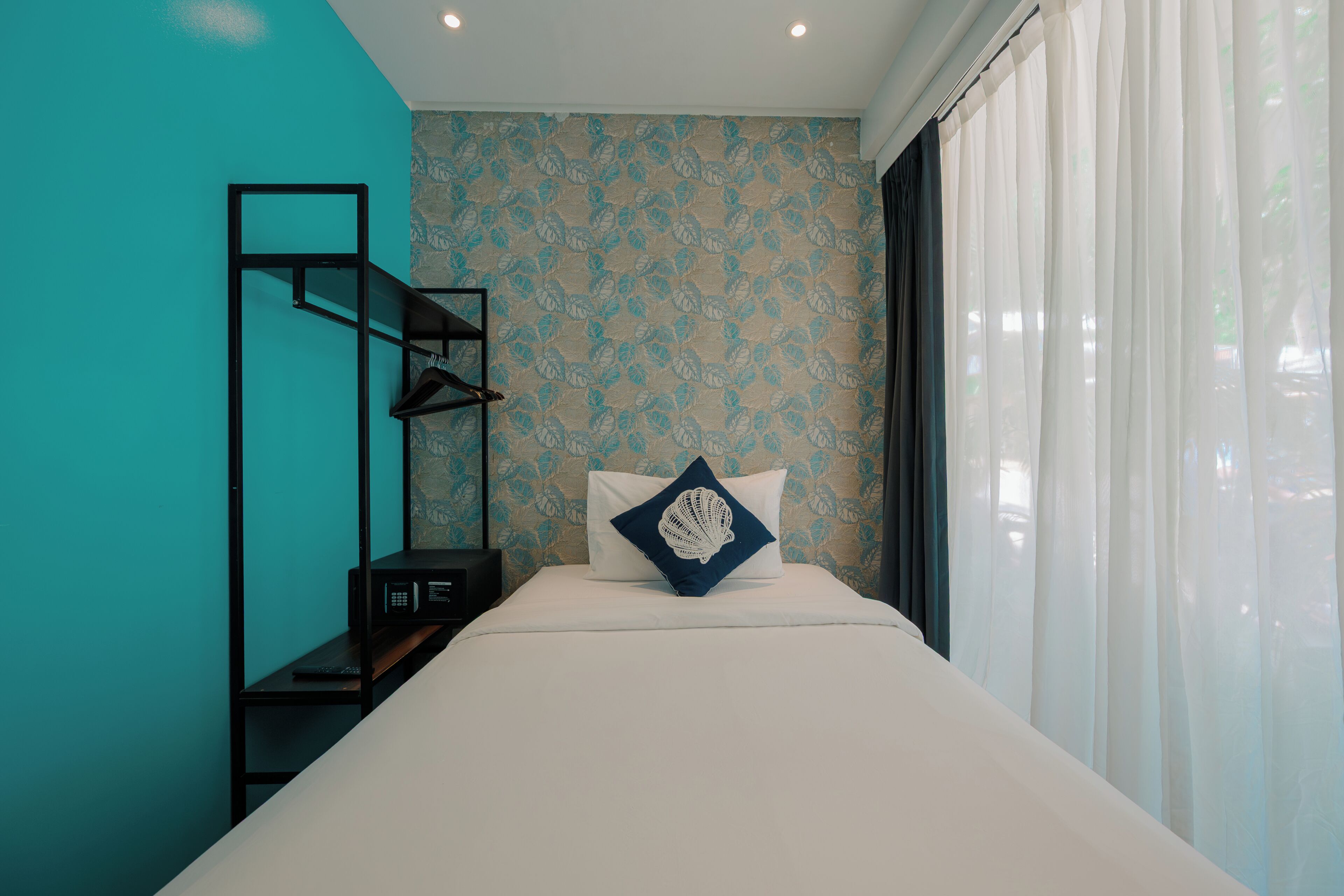 Un dormitorio con una cama, una estantería y un papel tapiz estampado.