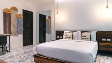 Un dormitorio con cama, dos puertas, una silla, lámpara colgante y suelo estampado.