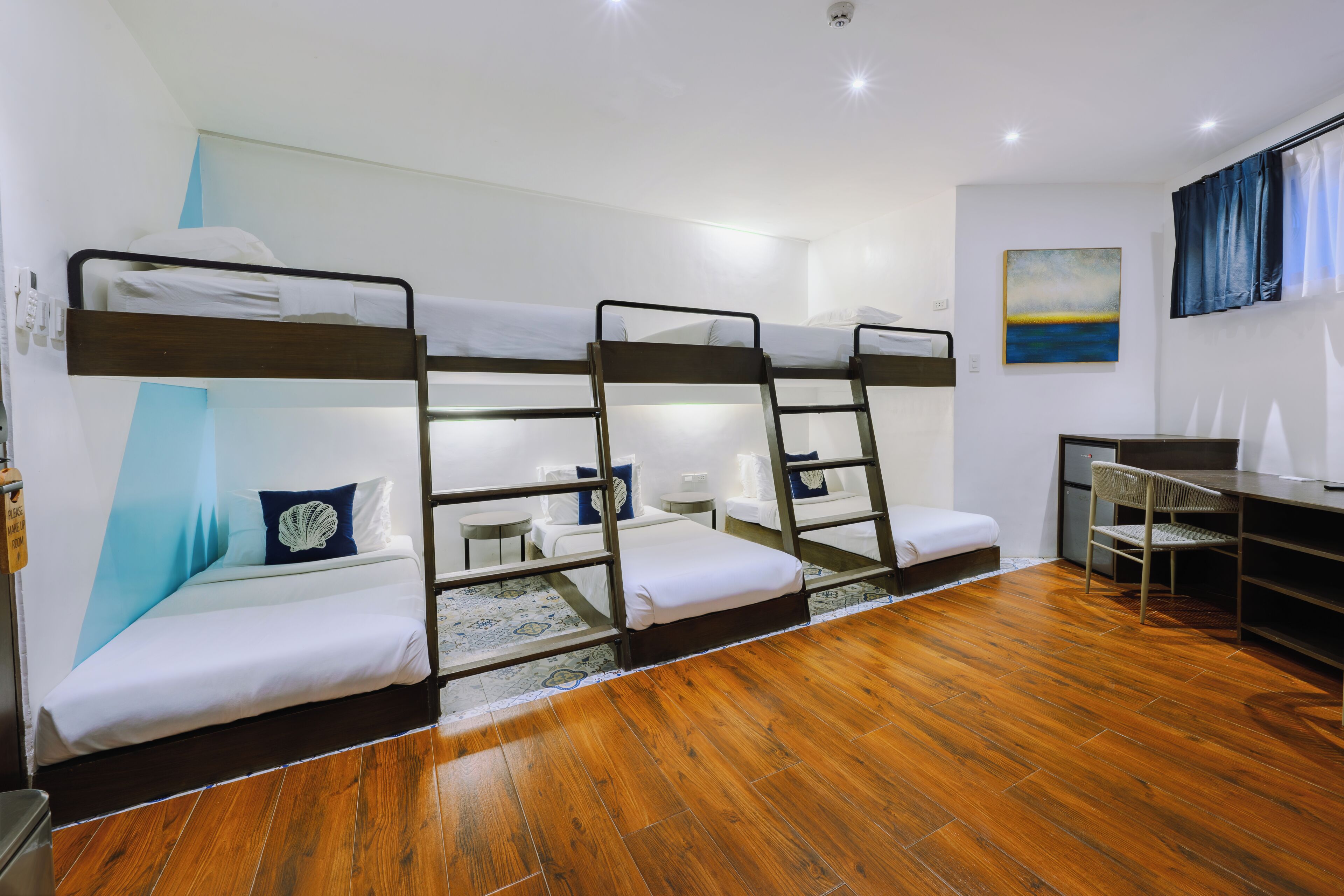 Een slaapkamer met een stapelbed, bureau en stoel, een klein tafeltje en een schilderij aan de muur.