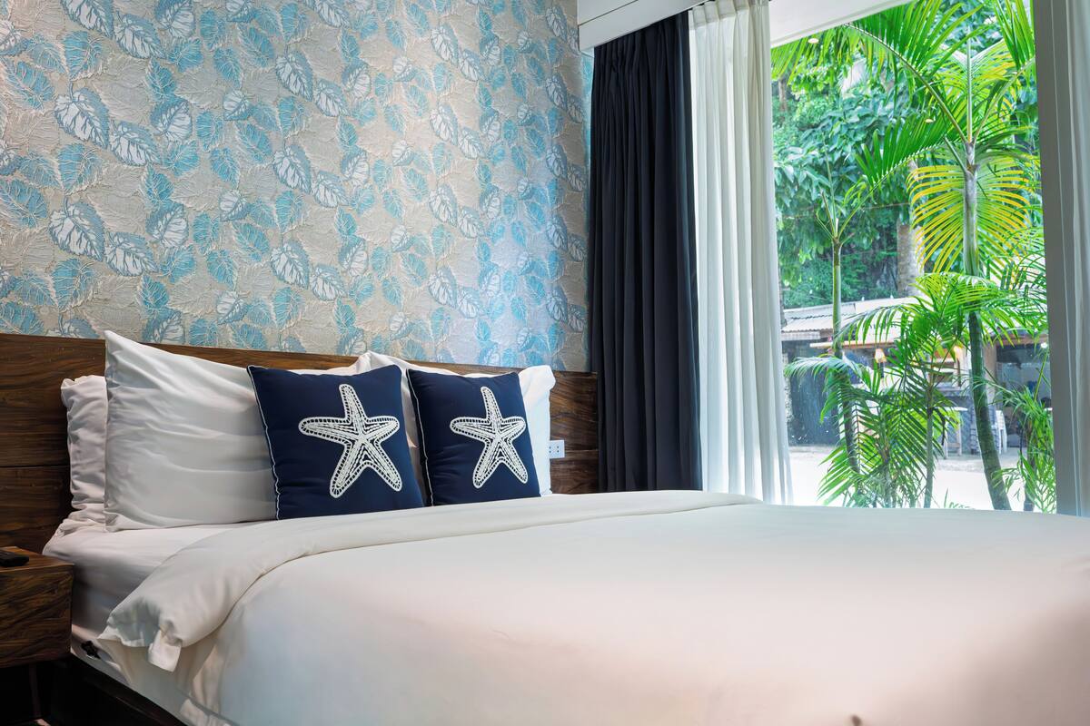 A hotel room with a bed, a nightstand, and a window with curtains.