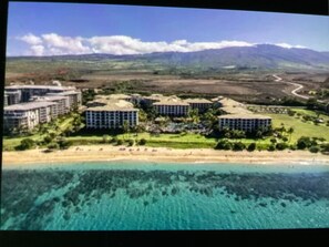 Un resort costero con varias edificaciones, una playa y aguas turquesas cristalinas.