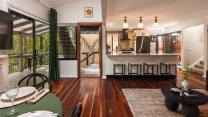 Un intérieur moderne comprenant un coin repas, une cuisine et un escalier menant à une terrasse extérieure.