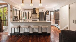 Une cuisine moderne dotée d’un îlot central, de tabourets de bar et d’un grand réfrigérateur.