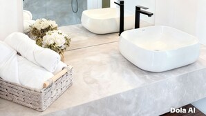 Een moderne badkamer met een grote spiegel, twee wasbakken, een douche en een rieten mand met handdoeken.