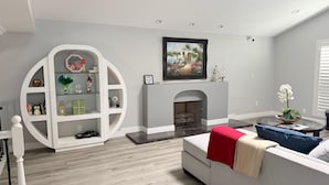 Ein modernes Wohnzimmer mit Kamin, einem weißen Dekobrett und einem Sofa mit roter Decke.