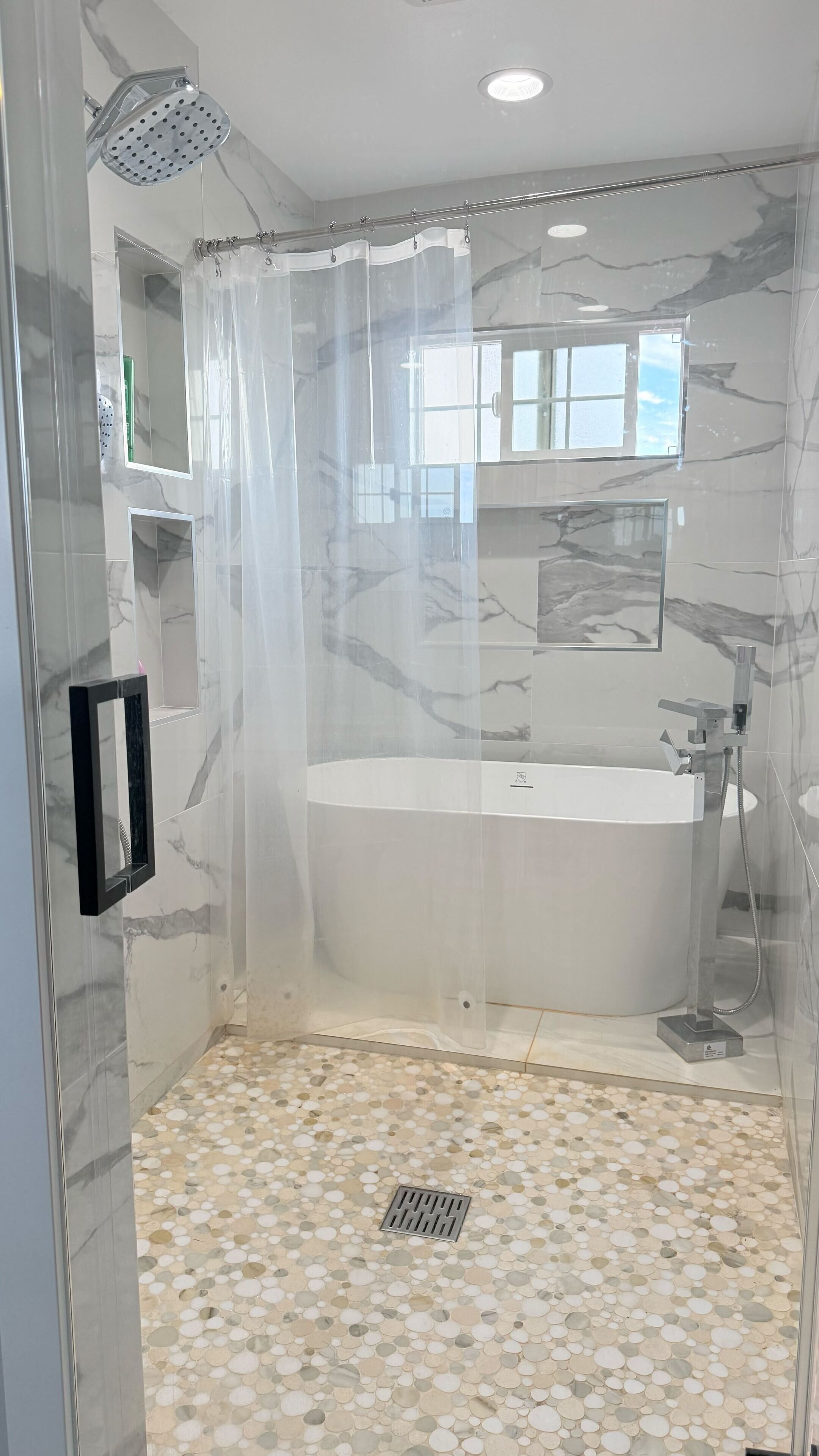 A modern bathroom with a freestanding bathtub, a showerhead, and a glass shower enclosure.