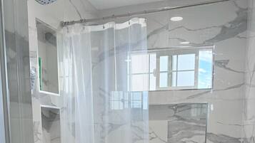 A modern bathroom with a freestanding bathtub, a showerhead, and a glass shower enclosure.