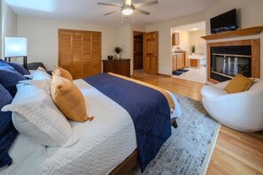Ein Schlafzimmer mit Bett, Sessel, Fernseher, Kamin und Küchenzeile.
