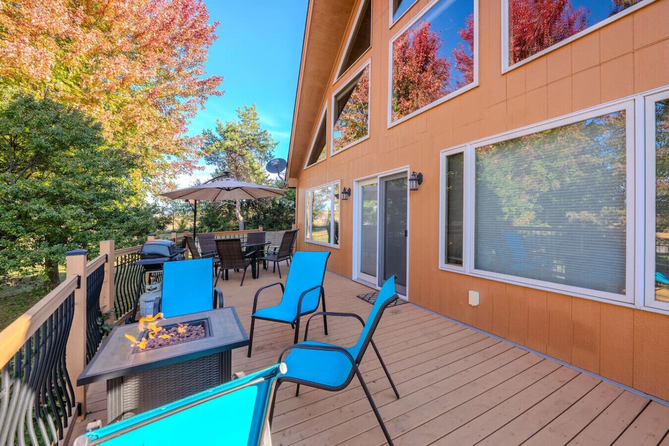 Una terraza con mobiliario exterior, una chimenea y vistas a árboles.