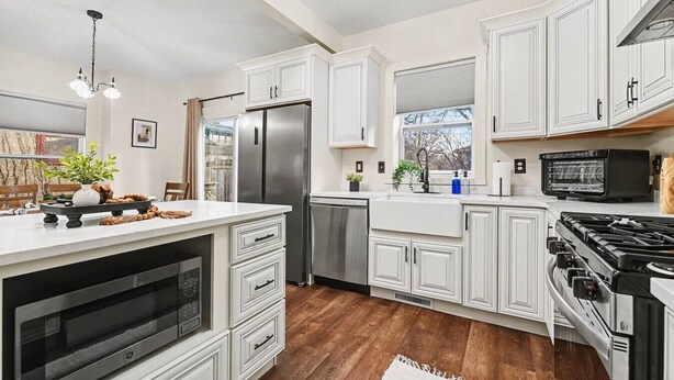 A modern kitchen with white cabinetry, a stainless steel refrigerator, a built-in oven, and a microwave. - Haven on Main - 4 Bed 2 Bath (Sioux Falls)