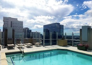 Ein Pool auf dem Dach mit Liegestühlen und Blick auf Stadtgebäude.