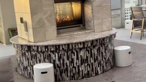 Un moderno caminetto da esterno con rivestimento in pietra e fuoco acceso all'interno.