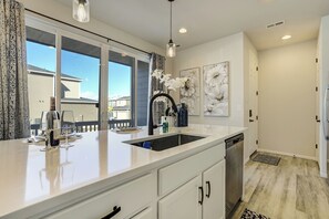 Une cuisine moderne dotée d’un grand îlot central, de meubles blancs et d’un lave-vaisselle.