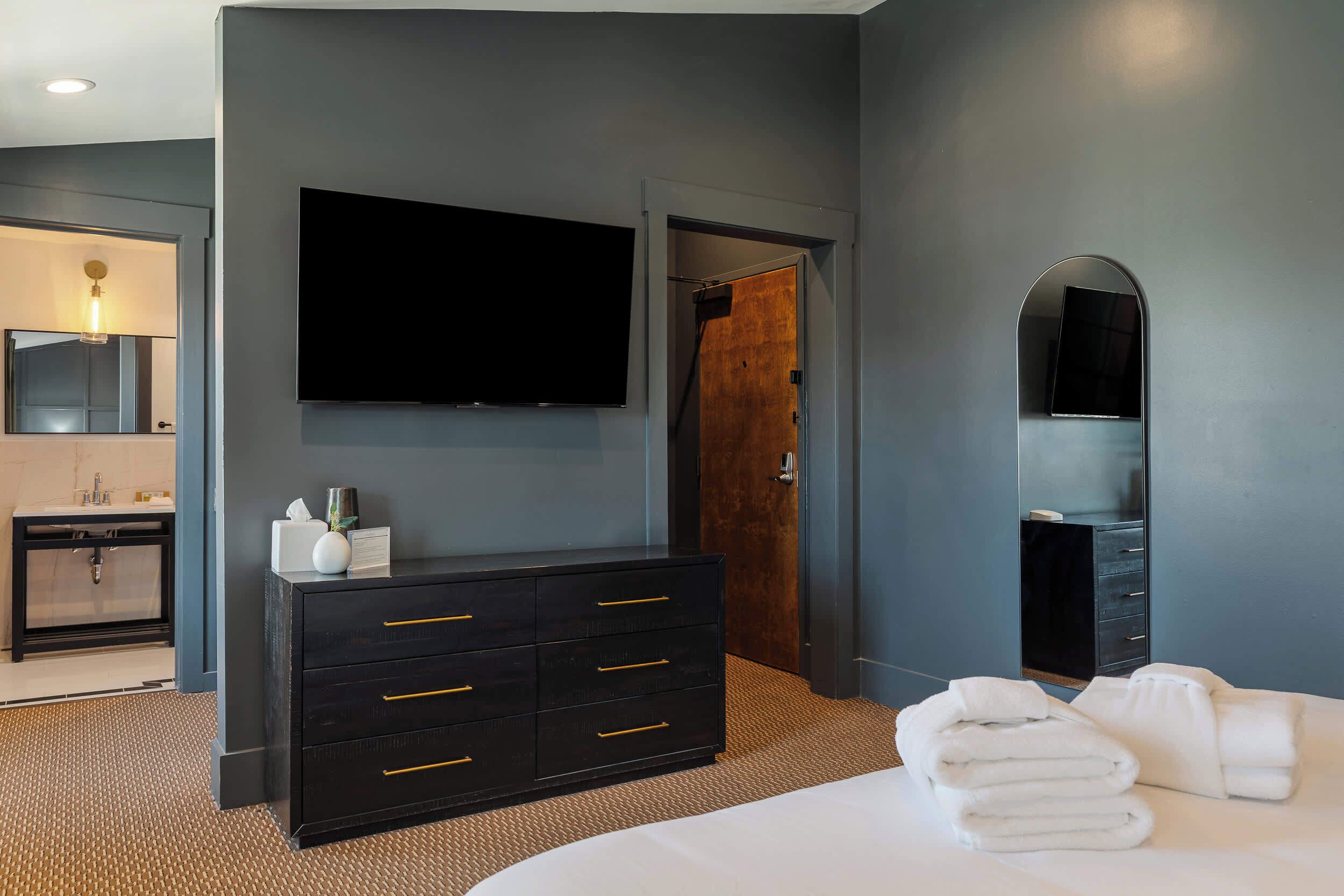 A hotel room with a bed, a dresser, a television, and a mirror.