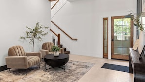Een moderne lobby met een trap, een receptiebalie en een zithoek met een bijzettafeltje.