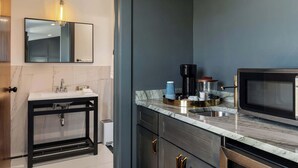 Een moderne keuken met een marmeren aanrecht, een ingebouwde magnetron en een koffiezetapparaat.