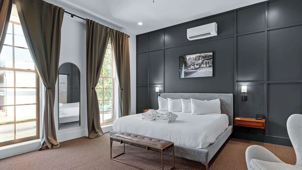 Moderni hotellihuone, jossa on suuri sänky, penkki, työpöytä ja näkymä ulos.