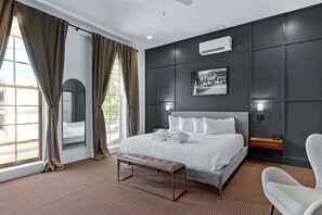 Camera d'albergo moderna con un letto grande, una panca, una scrivania e vista sull'esterno.