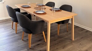 Ruokailutila, jossa on puinen pöytä, kuusi tuolia ja vaaleanvärinen seinä.