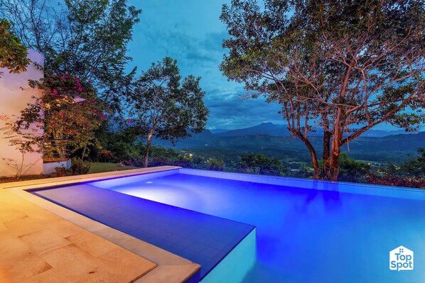 A swimming pool with a view of mountains at dusk.