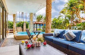 Ein Poolbereich mit einer Couch, Liegestühlen und einem Tisch mit Getränken und Früchten.
