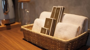 Ein Korbwesen mit verschiedenen Gegenständen, darunter ein weißes Handtuch und eine Broschüre mit dem Logo 'Z Garden Hotel'.