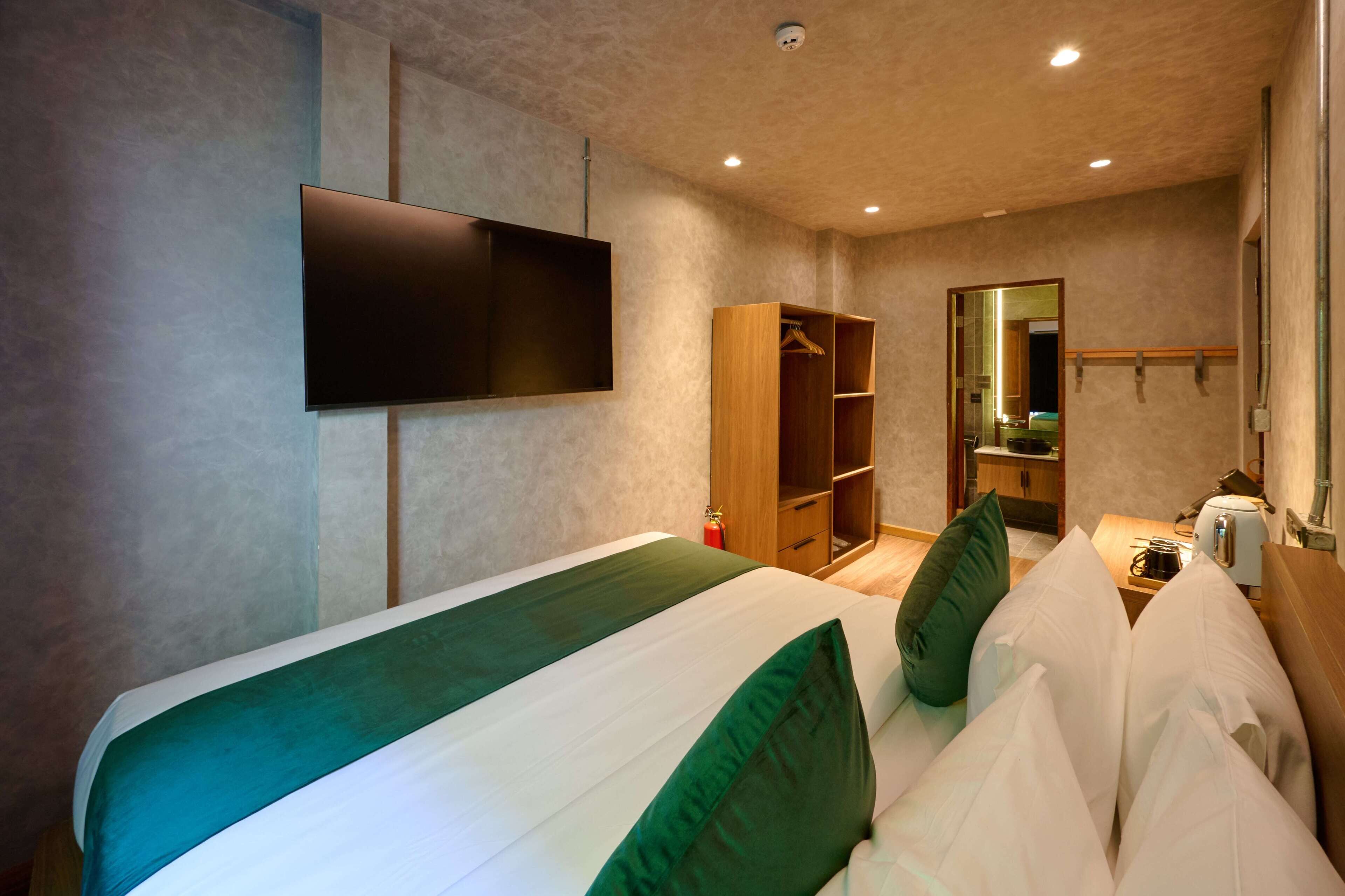 Une chambre d’hôtel avec un lit, une télévision, une armoire et un miroir.