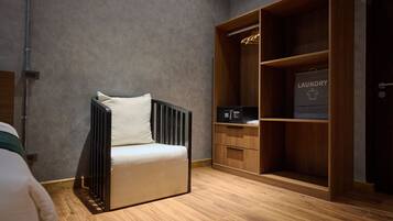 A room with a modern chair, a wooden wardrobe, and a laundry bag visible.