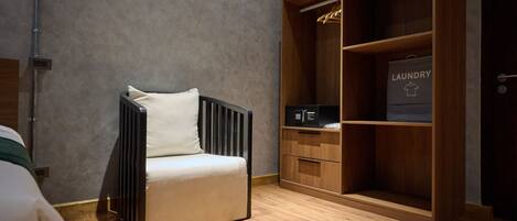 A room with a modern chair, a wooden wardrobe, and a laundry bag visible.