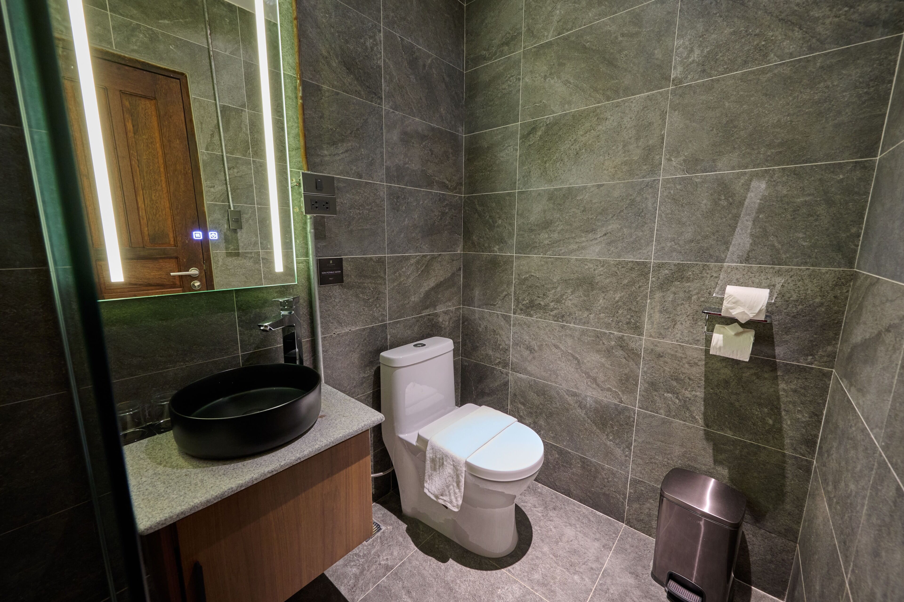 Un baño moderno con lavamanos, inodoro y espejo.