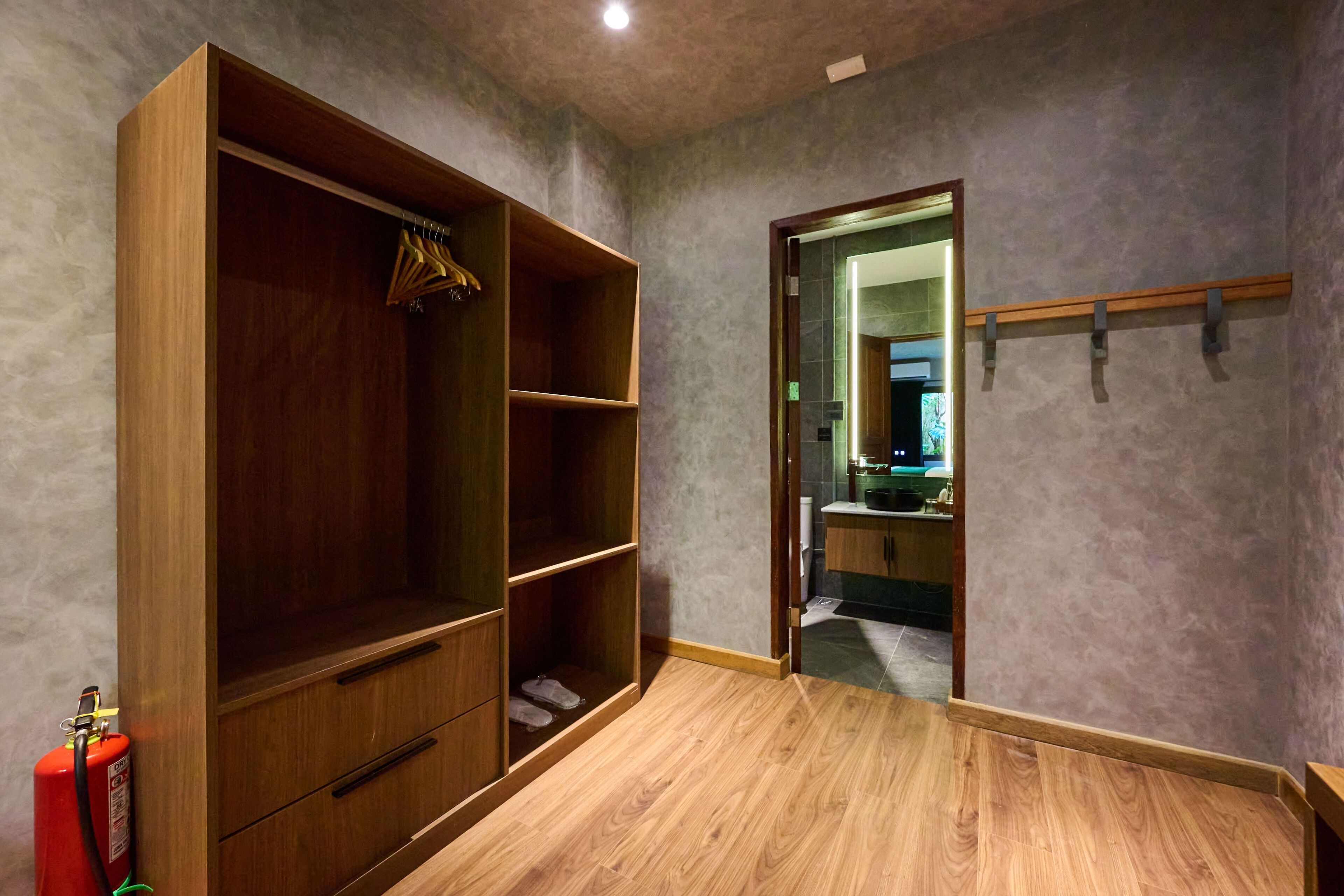 Ein Zimmer mit einem Holzschrank, einem Spiegel und einer Tür zu einem anderen Raum.